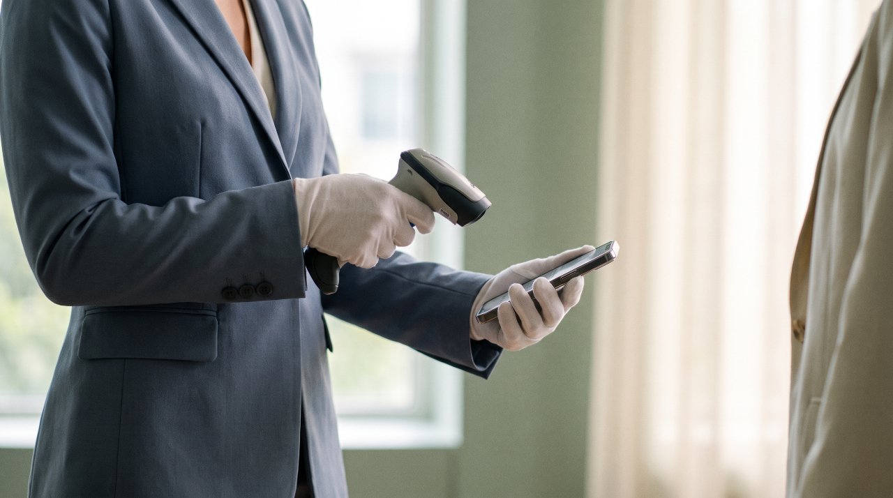 Staff member using a sleek laser scanner for digital ticketing check-in at an event.